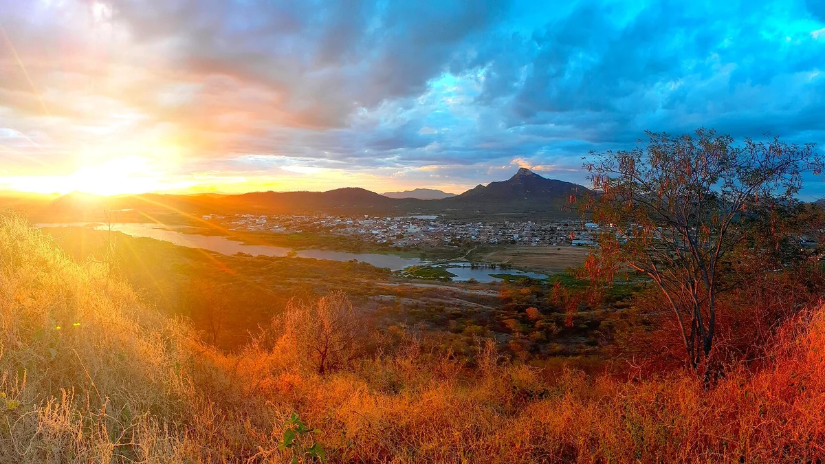 Pôr do sol sobre o vale no sertão da Paraíba, com serra e açude ao fundo